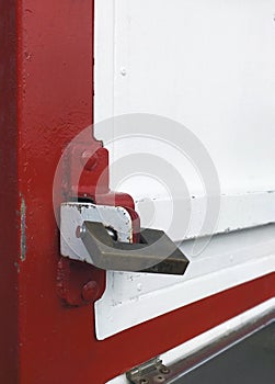 Side view of Old iron padlock on red and white metal door. Closed old door metal lock background