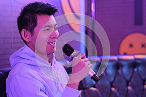 Asian young man holding microphone singing at karaoke