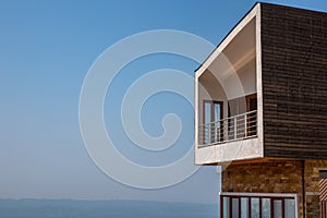 Side view of one modern penthouse apartmen with large balcony. Blue sky and horizon in the background.