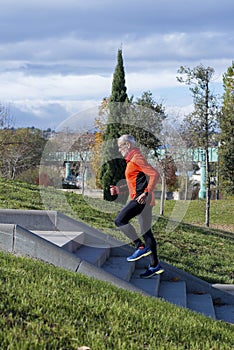 Side view of one senior caucasian athlete man training running up and down the stairs outdoors in a park in a sunny day