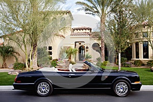 Side view of a open roof car in front of villa