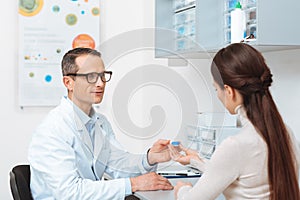 side view of ophthalmologist in eyeglasses giving contact lens to patient