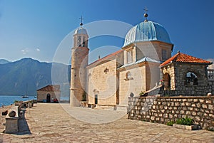 Side view of Our Lady of the Rocks islet off the coast of small old town Perast in Bay of Kotor, Montenegro mountainous background