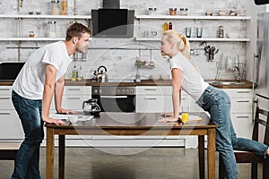 side view of passionate young couple looking at each other while reading and drinking coffee with juice