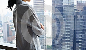 Side view of pensive woman standing looking out of window enjoying city view and contemplating. thinking of business success