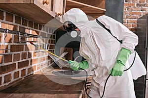 side view of pest control worker spraying pesticides on shelves