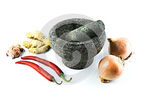 Pestle and mortar with the onions, garlic, red chilies and ginger over white background