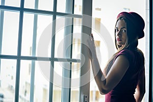 Side view photo of attractive stylish lady in red hat standing in doorway