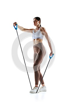 Side view photo of fitness model in activewear performing workout with stretch band against white studio background