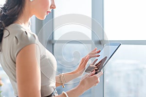 Side view photo of young female teleworker using tablet, searching and browsing information via wi-fi connection photo