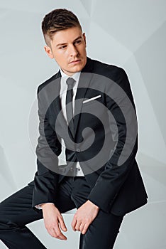 Young business man in modern suit sitting on chair