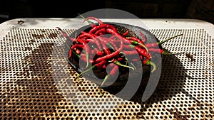 Side view of a pile of red chilies on a mortar on a rusty iron base