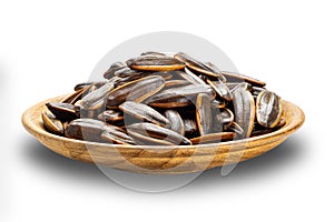 Side view pile of salted sunflowers seeds in wooden plate isolated on white background