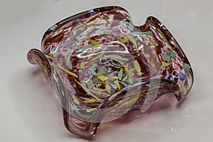 a side view of a pink or red colored blown glass candy dish
