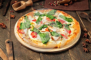 Side view on pizza napoli with spinach and tomato