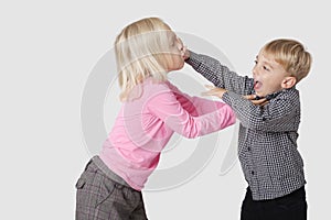 Side view of playful young boy and girl over white background