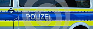 Side view of a police bus with blue and yellow paint with the German inscription