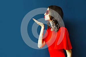 side view portrait beautiful young woman blowing red lips sending sweet air kiss wearing heart shaped sunglasses on blue wall