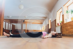 Side view portrait of beautiful young woman working out, resting after doing yoga exercises, lying in Savasana, Corpse