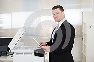 Businessman Using Photocopy Machine In Office