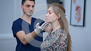 Side view portrait of Caucasian woman standing in plastic surgery clinic with blurred Middle Eastern man talking