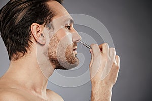 Side view portrait of a confident man removing nose hair