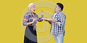 Side view portrait of couple of happy friends, man and woman in casual checkered shirt standing and husband giving present gift