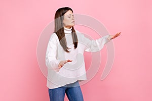 Side view portrait of disoriented girl walks with eyes closed, holding out her hands to find road.