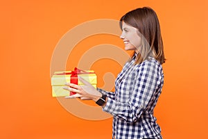 Side view portrait of generous friendly woman with brown hair in casual checkered shirt. indoor studio shot isolated on orange