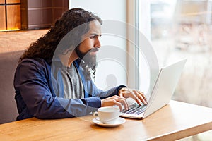 Side view portrait of handsome intelligence young adult man freelancer in casual style sitting in cafe and searching information
