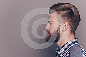 Side view portrait of handsome thinking stylish young man looking away with copy spase on gray wall