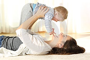 Happy mother on the floor raising her baby son photo