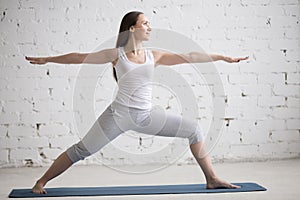 Side view portrait of happy woman doing Warrior II Pose