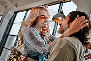 Side view portrait of a loving young couple embracing at home. Christmas lights background. Bottom view