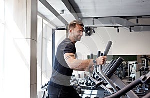 Side view portrait of man workout on a fitness machine at gym