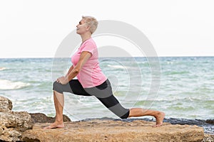 Side view portrait of mid age woman stretching on the beach