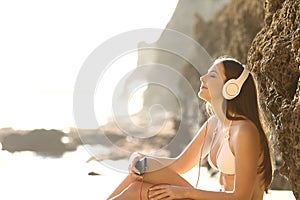 Relaxed sunbather listens to music on the beach photo
