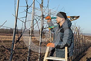 Side view portrait of the serious young man in casual clothes, with white airpods in his ears stands on the stepladder