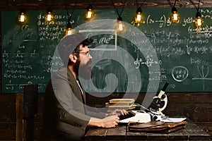 Side view portrait of stylish man with old school vintage typewriter on wooden table, typing story