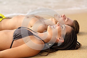 Happy sunbathers sunbathing on the sand of the beach photo