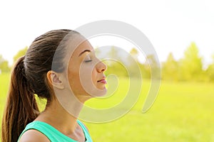 Side view portrait of woman relaxing breathing fresh air deeply in the park. Copy space