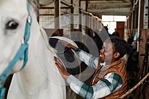 Young Woman Preparing Horse in Stables