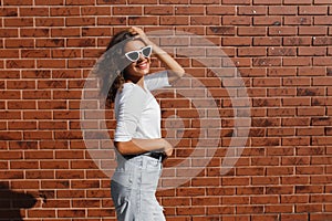 Side view portrait of young beautiful happy woman in casual cloth against brick wall