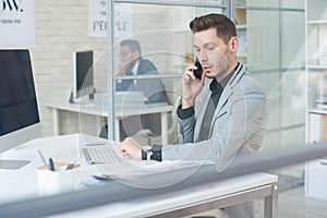 Young Businessman Speaking by Phone at Work