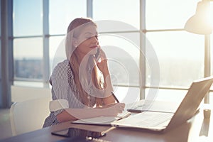 Side view portrait of young businesswoman having business call in office, her workplace, writing down some information