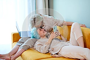 Side View Portrait Of Young Lesbian Couple Having Rest On Sofa At Home, Relaxed