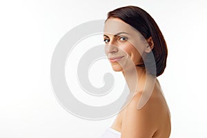 Side view portrait of young smiling woman with naked shoulders and natural facial makeup looking at camera. Beauty face