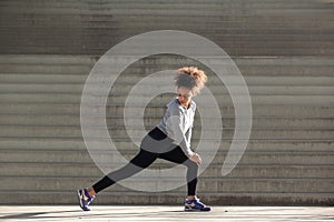 Side view portrait of a young woman stretching leg muscles