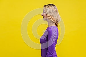 Side view of positive successful woman looking happy and content, empty copy space.  on yellow background