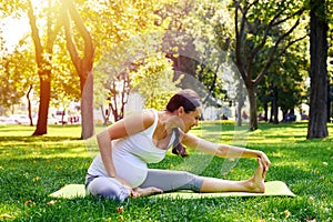 Pregnant woman doing relaxing yoga workout in park